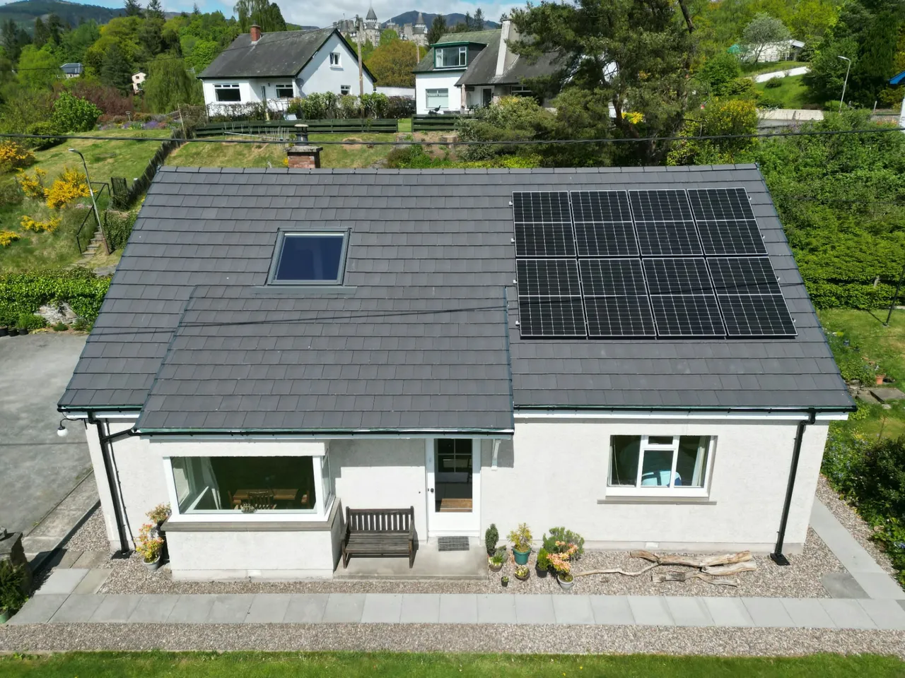 New grey tiled roof with rooflight and solar panels on a white rendered house